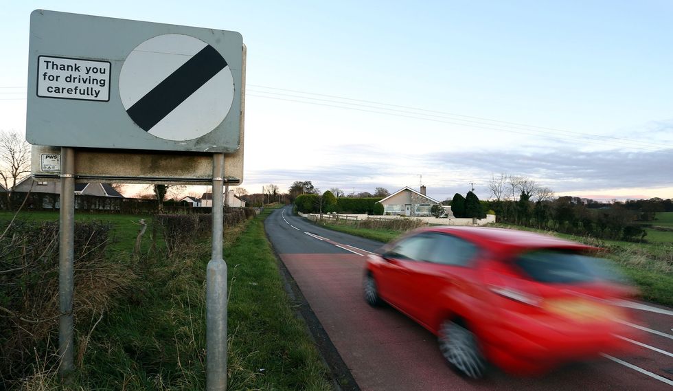 A car driving past a national speed limit sign