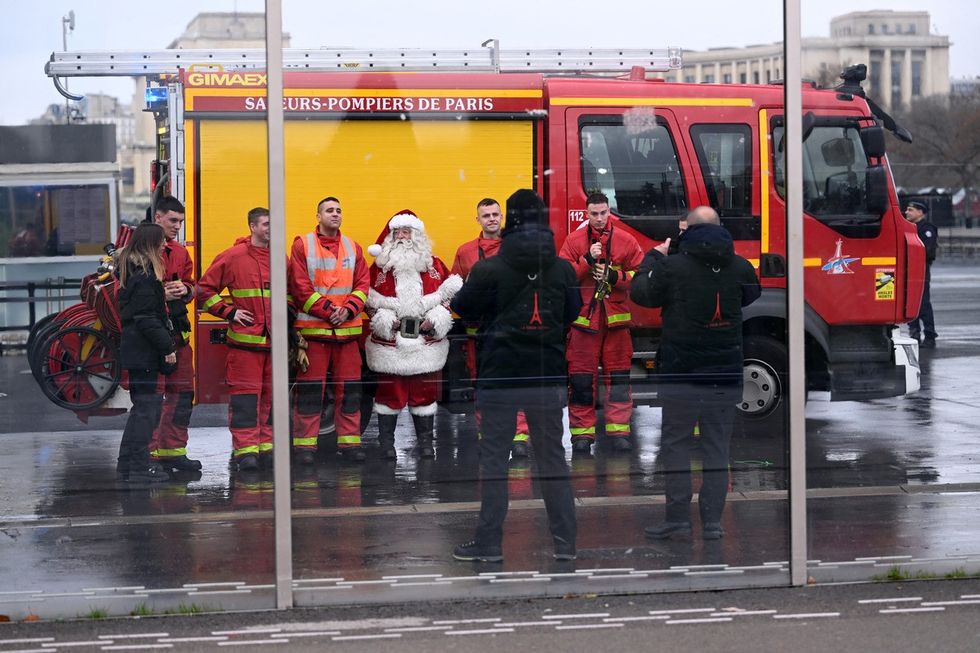 A Father Christmas stands with emergency services in Paris