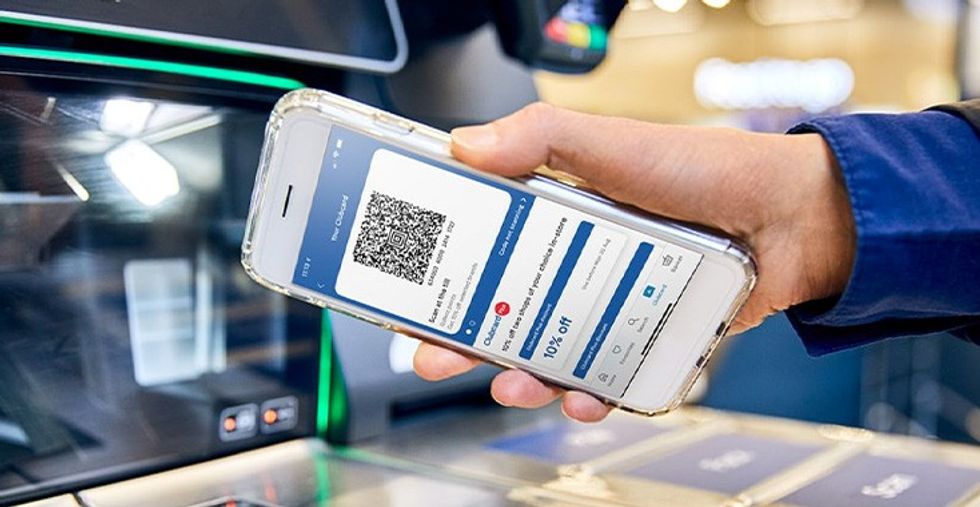 a hand scans the barcode built into the tesco clubcard app on an iphone 