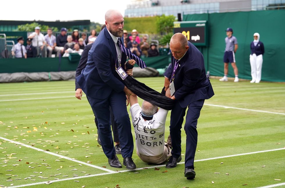 A Just Stop Oil protester is carried off court 18 after throwing confetti