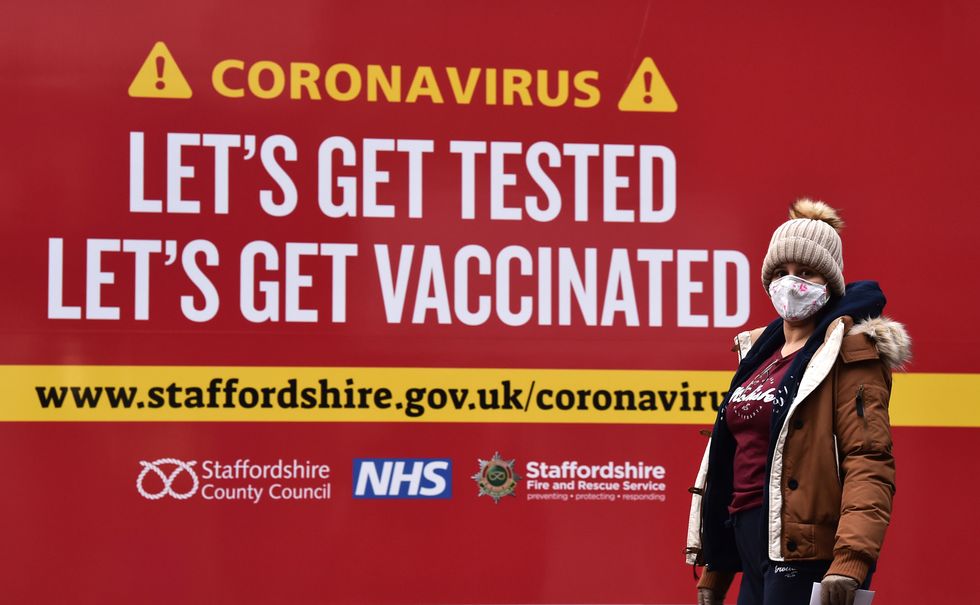 A lady walks coronavirus test centre which displays a sign saying 'Lets get tested, lets get vaccinated