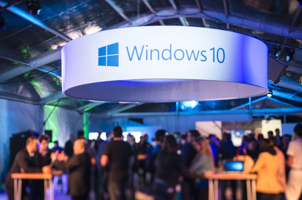 a large banner with windows 10 written on it hangs above a crowded launch party 