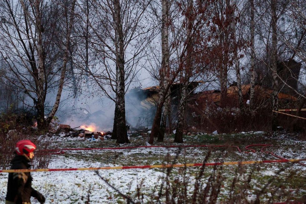 A Lithuanian rescuer walks past the wreckage of a cargo plane following its crash near the Vilnius International Airport