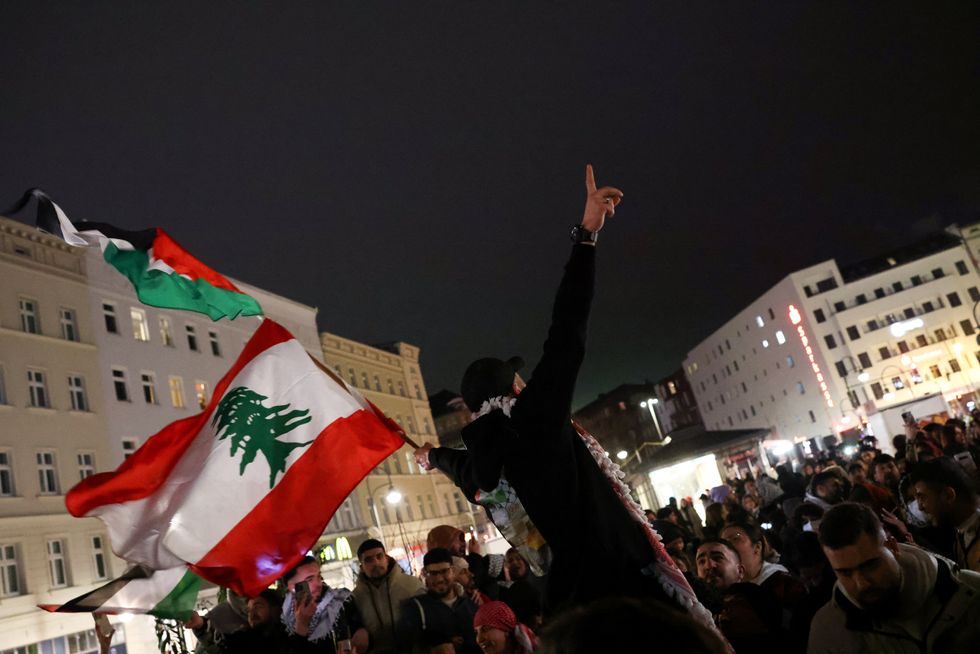 A man holds up a Lebanese flag, as Palestinian supporters celebrate news of a ceasefire with Israel, in Berlin, Germany