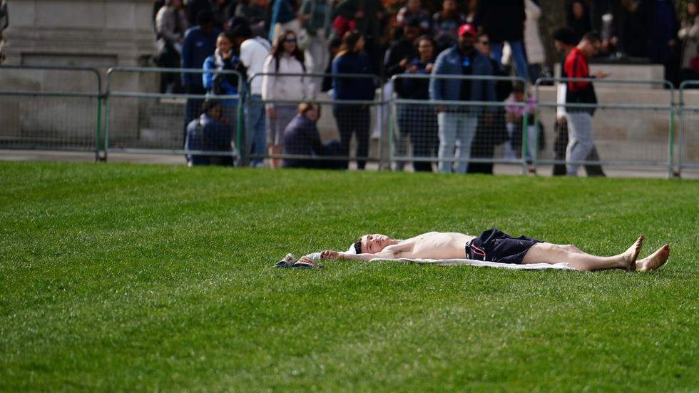 A man sunbathing in the warm weather in Parliament Square in London