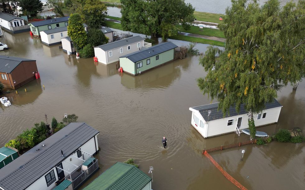 A man wades through floodwater at Cogenhoe Mill Holiday Park in Northamptonshire after the River Nene burst its banks