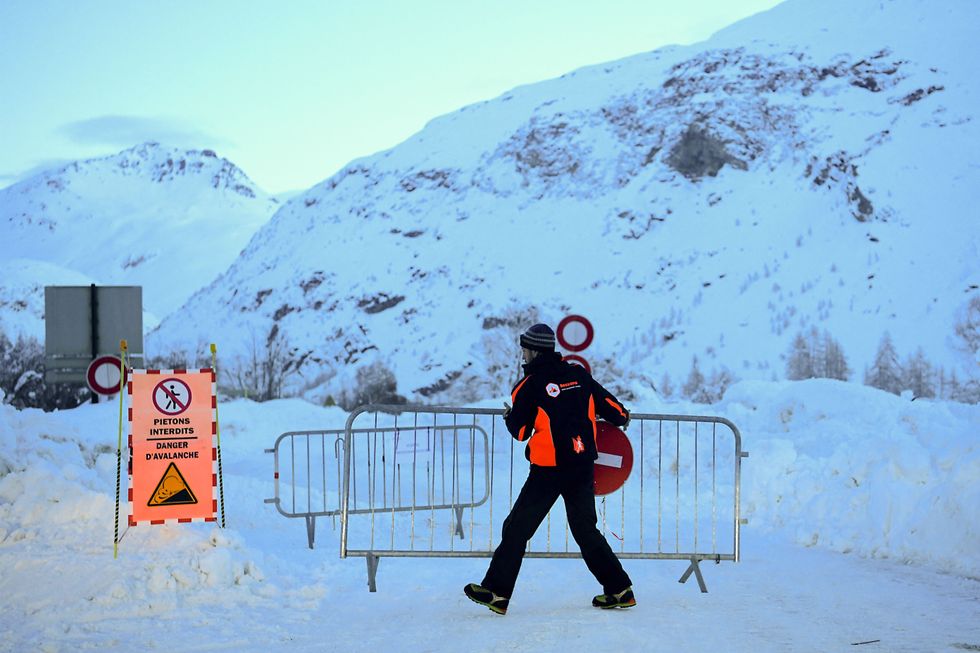 A municipal employee moves barriers as he temporarily opens a road for cars to drive in a convoy from Bessans to Bonneval-sur-Arc in the French Alps