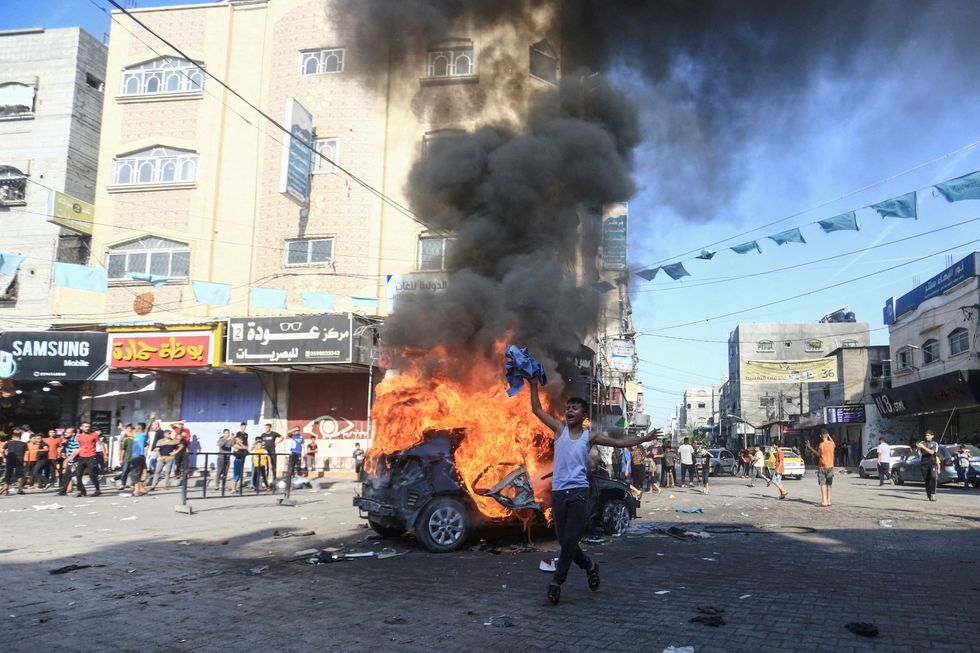 A Palestinian boy reacts next to a burning Israeli vehicle that Palestinian gunmen brought to Gaza after they infiltrated areas of southern Israel