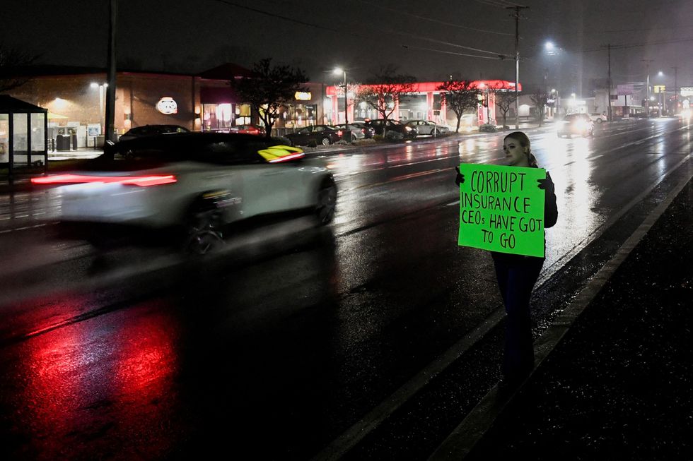 A person holds a sign while standing on the roadside near the McDonald's restaurant where Mangione was arrested