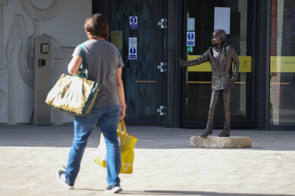 A person walks past he statue of climate change activist Greta Thunberg