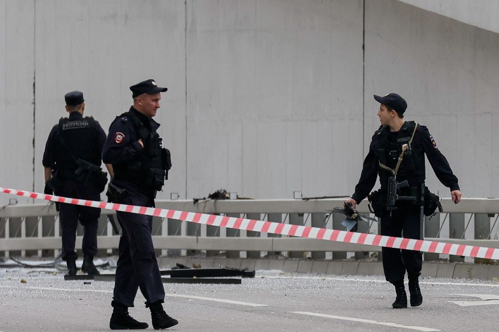 A police officer carries debris as they investigate a bridge near the site of a damaged building following a reported drone attack in Moscow