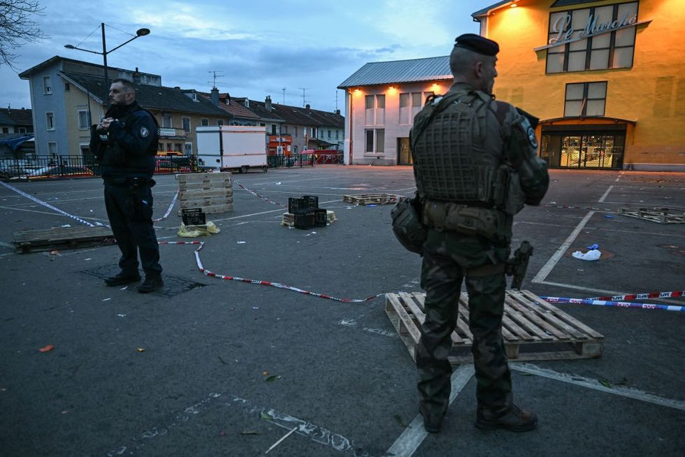 A police officer (L) and a military stand guard at the site of a bladed weapon attack where a man is suspected of killing one person