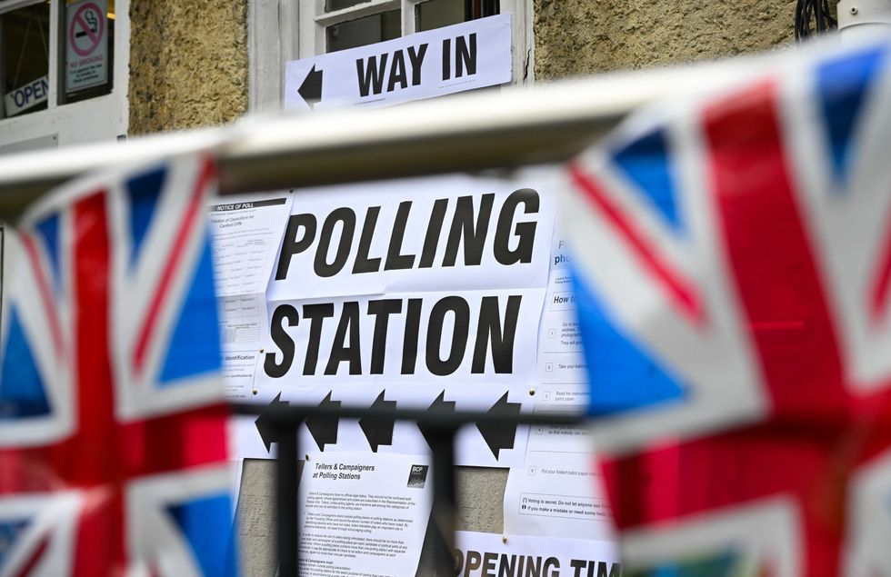 a polling station sign with union flags outside