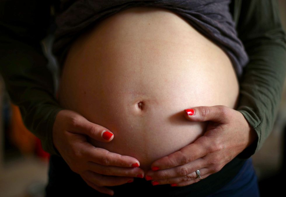 A pregnant woman holds her baby bump