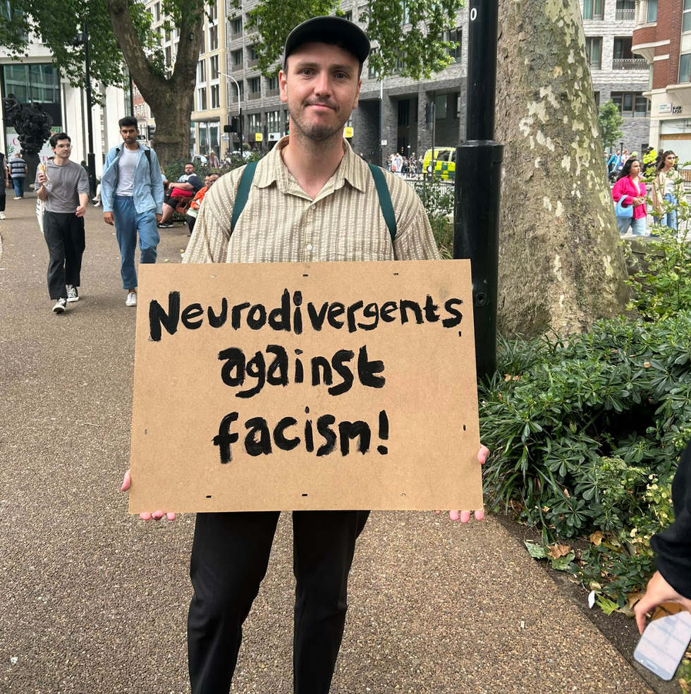 A protester holds up a 'neurodivergents against fascism' placard