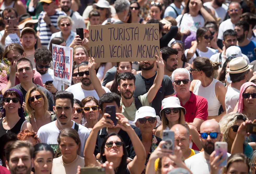 A protester is seen holding up a placard expressing his opinion during a demonstration against mass tourism