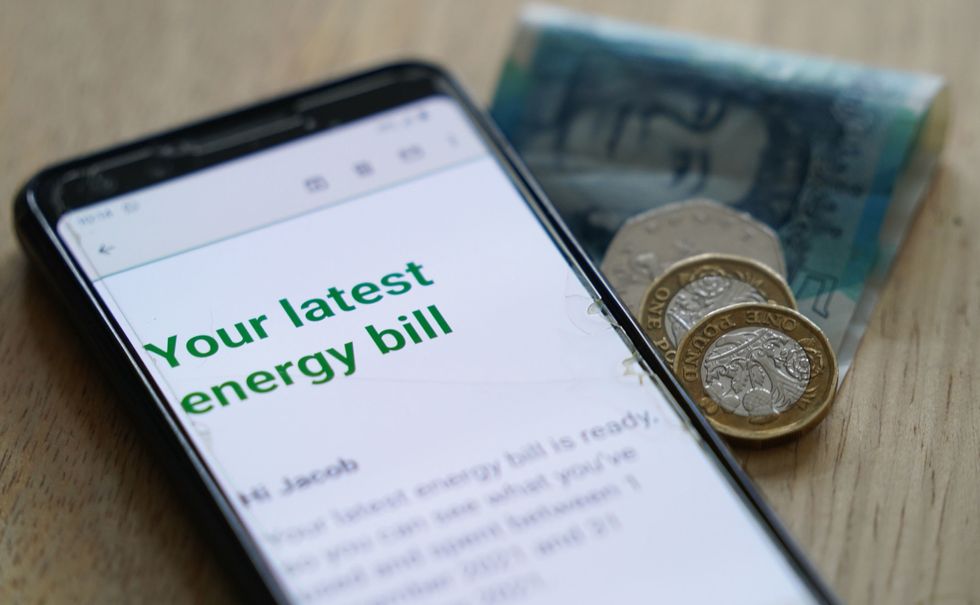 a smartphone displaying an energy bill next to some loose change