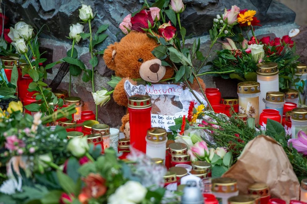 : A Teddy with the German word warum, meaning why, written below it sits amongst the flowers at the Johanniskirche left by the public in memory of the victims of a terror attack\u200b