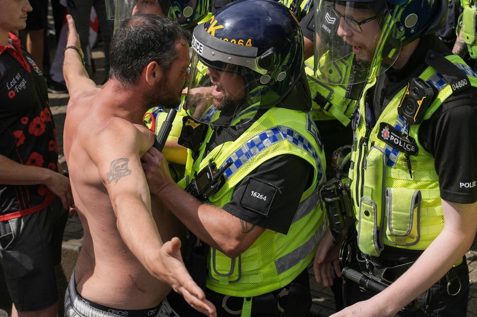 a topless man faces off against a police officer in uniform