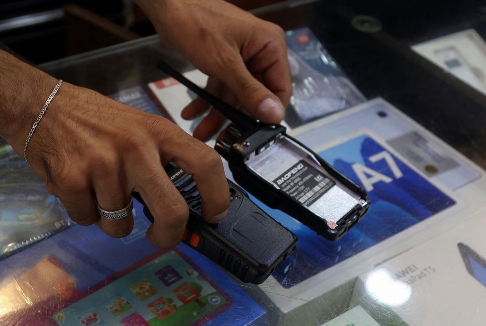 A vendor shows walkie-talkie devices without batteries, which he says he removed for safety reasons