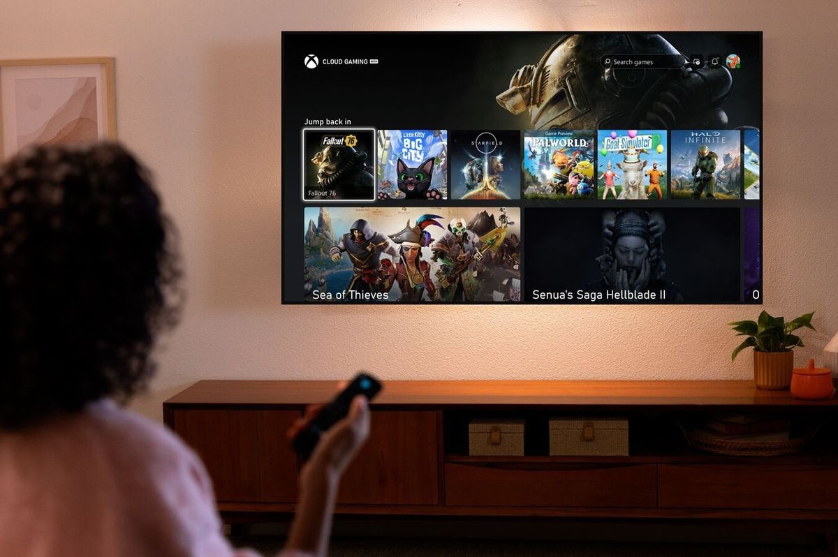 a woman holds a fire tv stcik remote with xbox games shown on-screen 