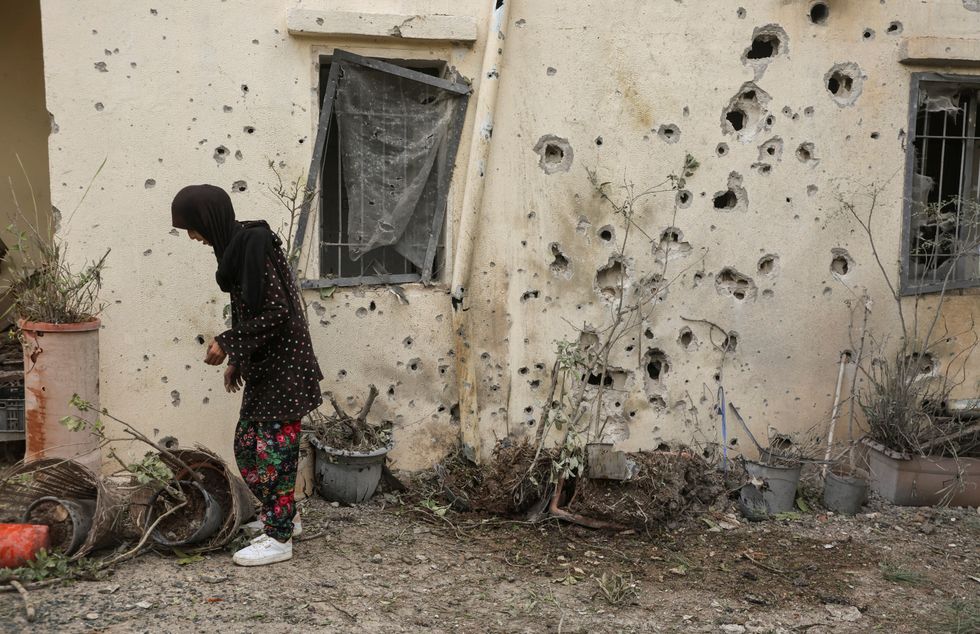 A woman stands near a bullet-riddled wall in Zahajra, near the border with Israel,