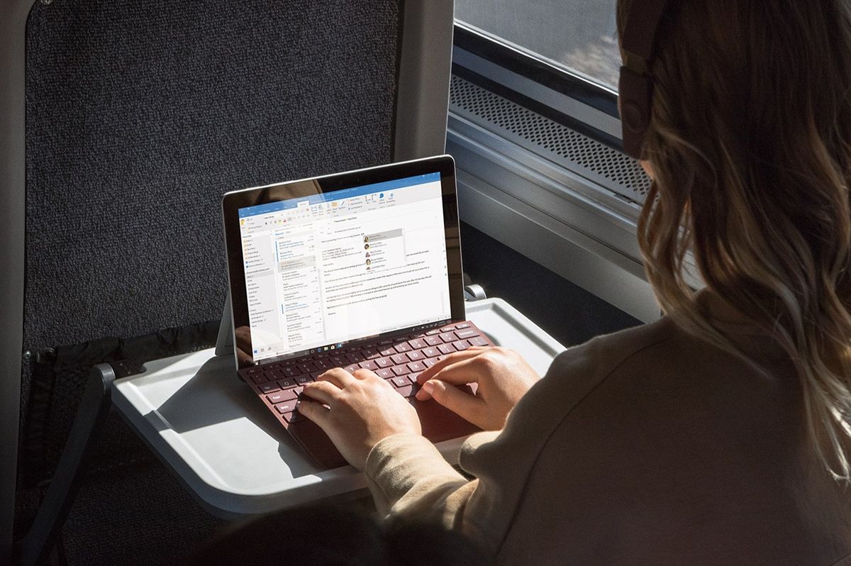 a woman typing on a keyboard on a surface tablet on the train  