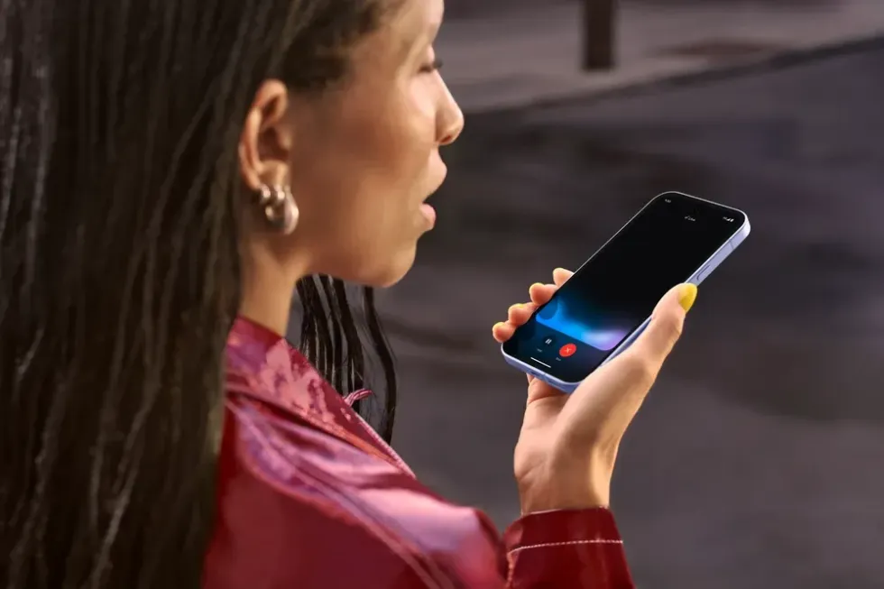 a woman wearing pink holds out her pixel 9a phone and talks to gemini live