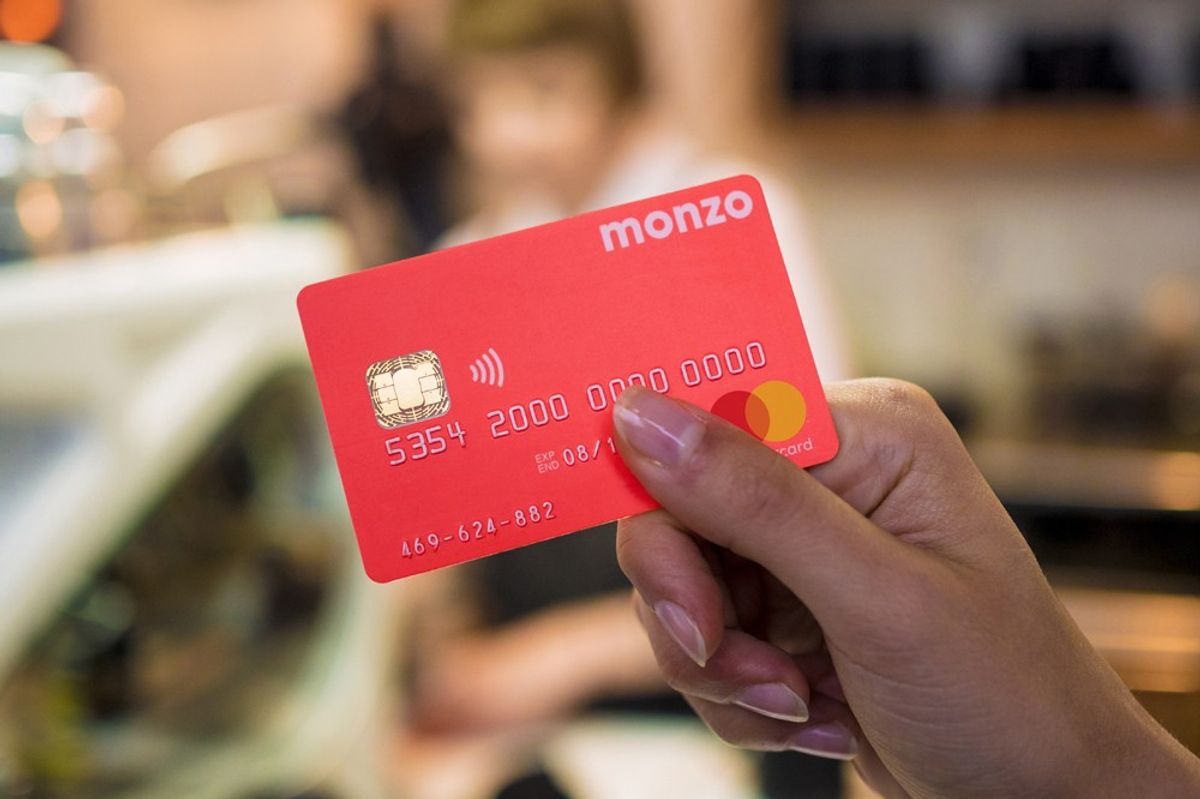 a womans hand holding a monzo bank card 