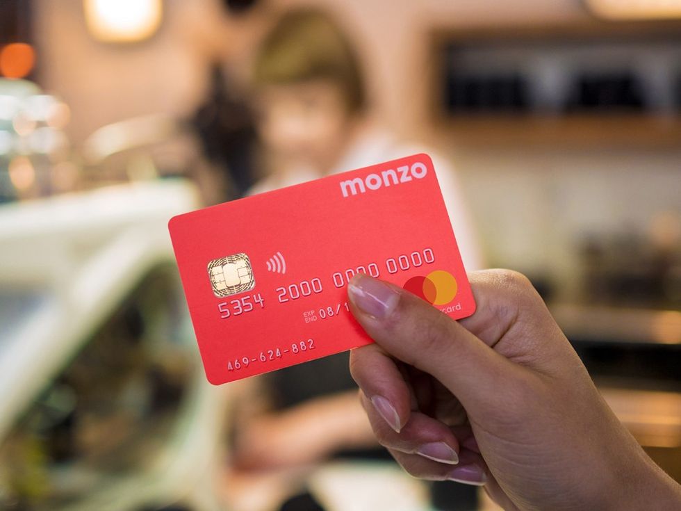 a womans hand holding a monzo bank card 