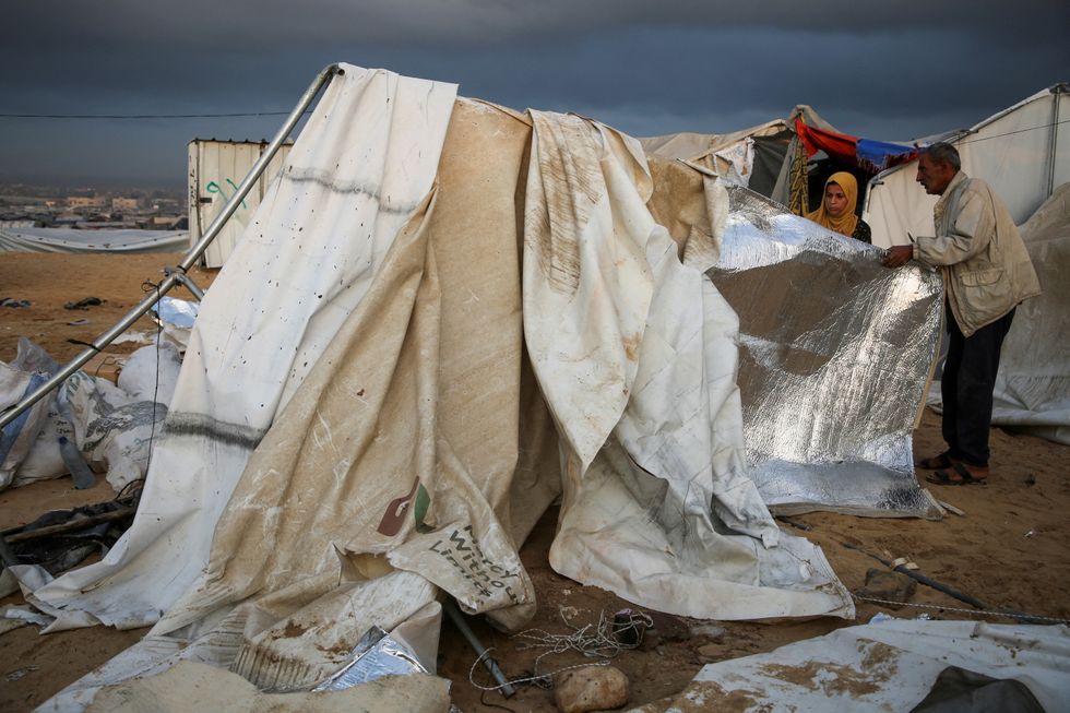 alestinians inspect the damage at the site of an Israeli strike on a tent camp sheltering displaced people