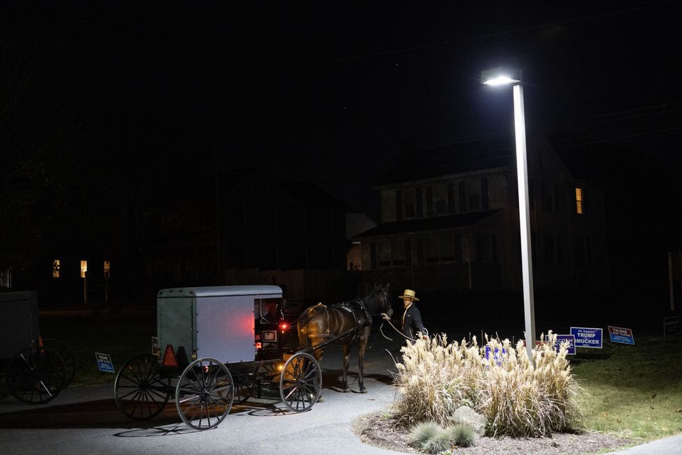 An Amish horse-drawn carriage rolls up next to a polling station\u200b