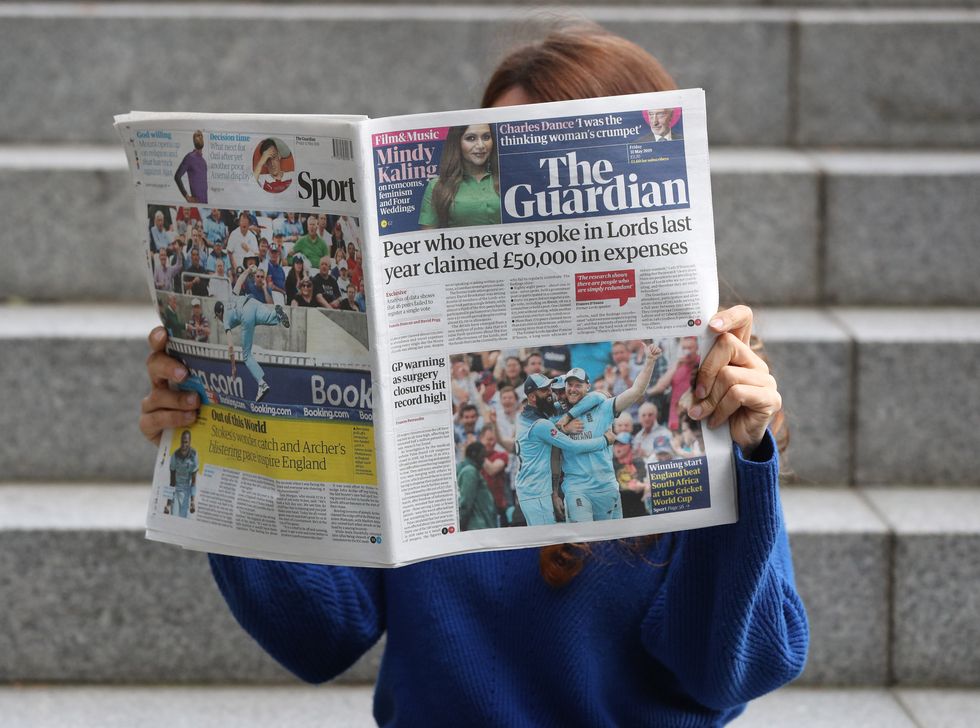 An image of a woman holding a copy of The Guardian