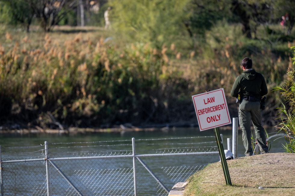 An officer stands guard on the banks of the Rio Grande river at Shelby Park on January 12, 2024 in Eagle Pass, Texas