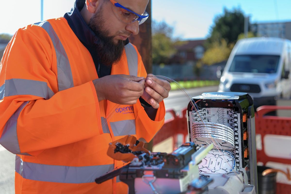 an openreach engineer wires up a fibre optic cable in an exchange cabinet 