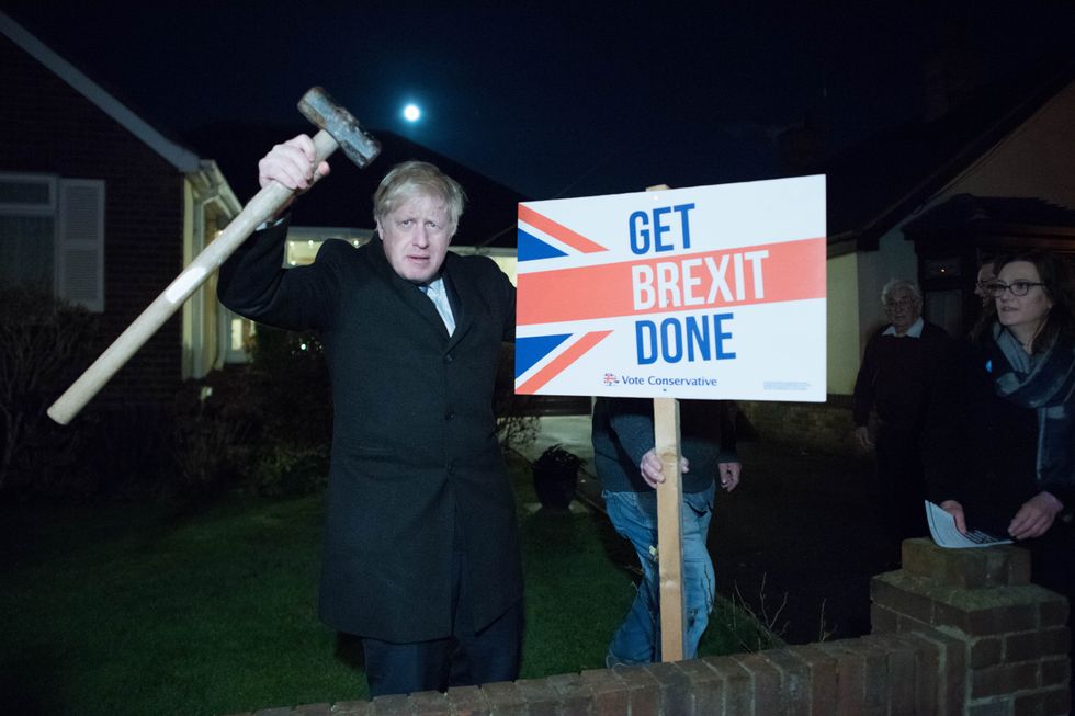 Boris Johnson hammers in a Conservative placard into a front garden whilst canvassing in Benfleet, Essex