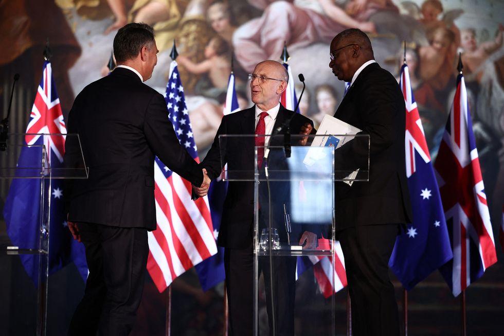 Britain's Defence Secretary John Healey (C), Australia's Defense Minister Richard Marles (L) and US Defense Secretary Lloyd Austin shake hands after taking part in a joint press conference during the AUKUS Defense Ministerial Meeting