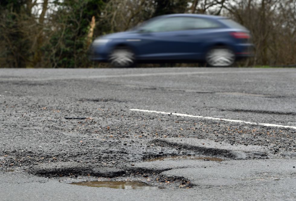 Car driving past a pothole on a road