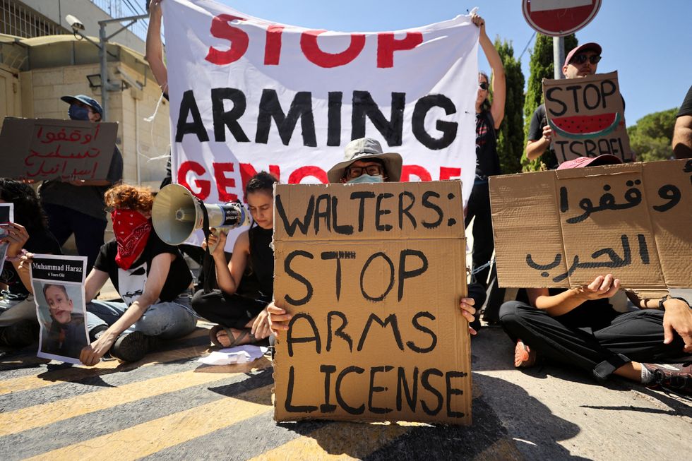 Chained Israeli protesters hold placards in a protest to call for an end to the war in Gaza, during Britain's Foreign Secretary David David Lammy's visit