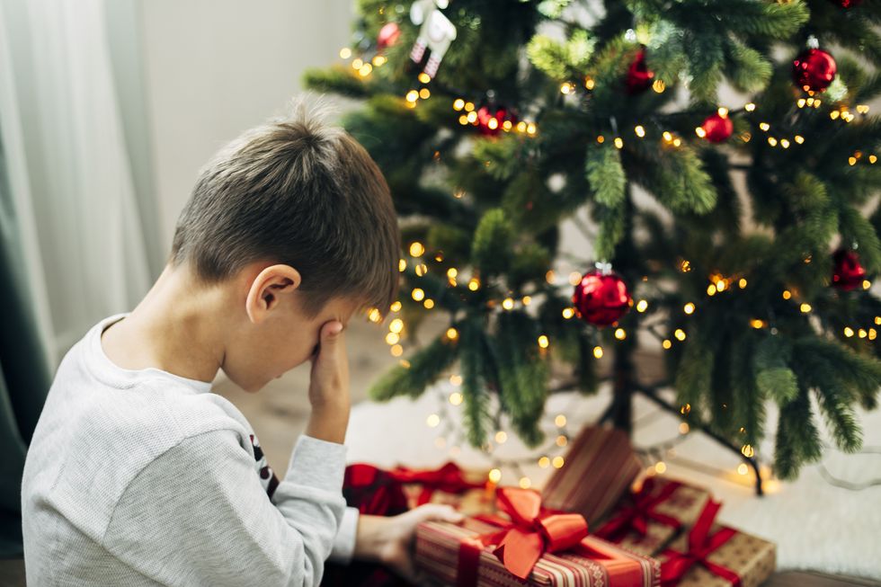 Child sobbing in front of Christmas tree