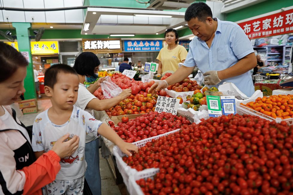 Customers select tomatoes at a stall inside a morning market in Beijing, China