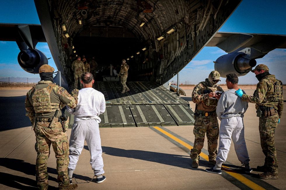 Detained migrants boarded onto military aircraft headed for detention facility at Guantanamo Bay