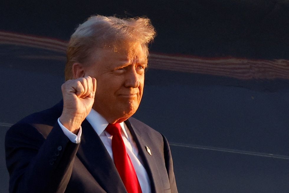 Donald Trump raises fist as he steps off the airplane