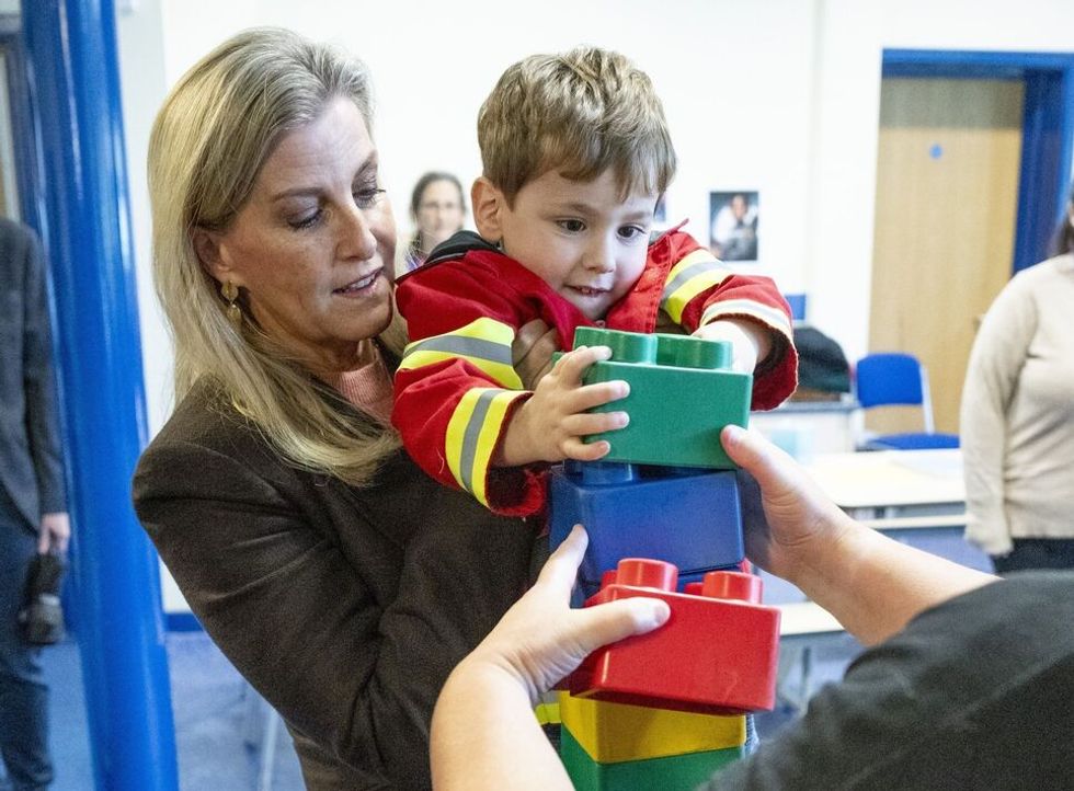 Duchess of Edinburgh helps young boy build a lego tower during royal