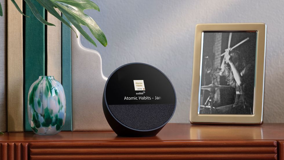 echo spot alexa speaker pictured in black next to a photo frame