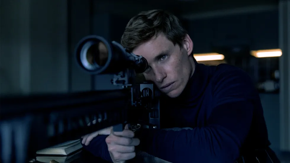 Eddie Redmayne starring in Day of the Jackal holding a sniper rifle in a still from the show