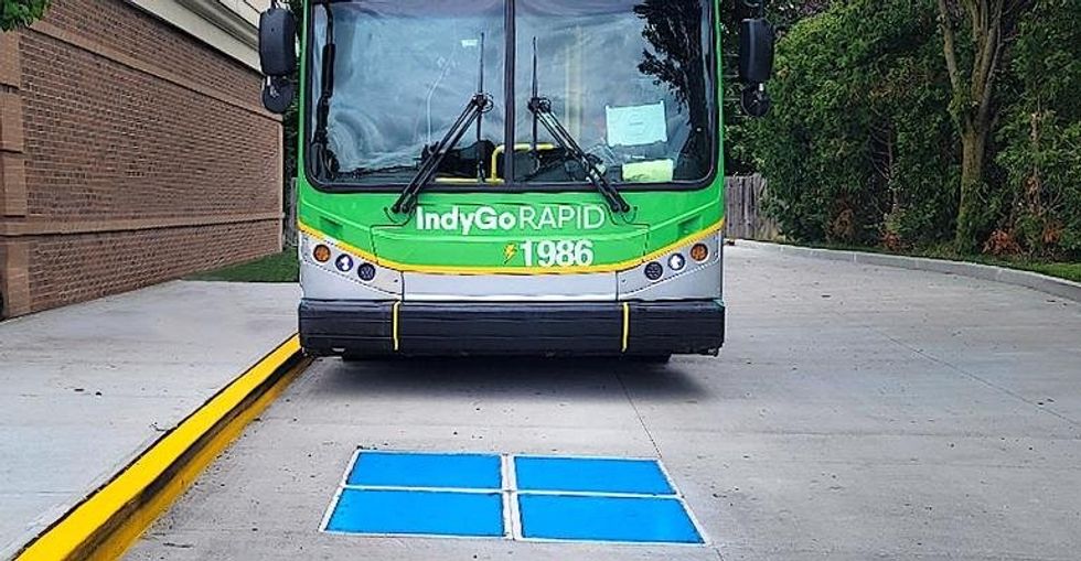 Electric bus preparing to stop over a wireless charging pad for recharging