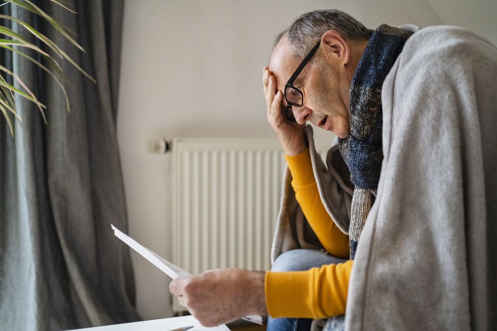 Energy bills statement being read by man under blanket