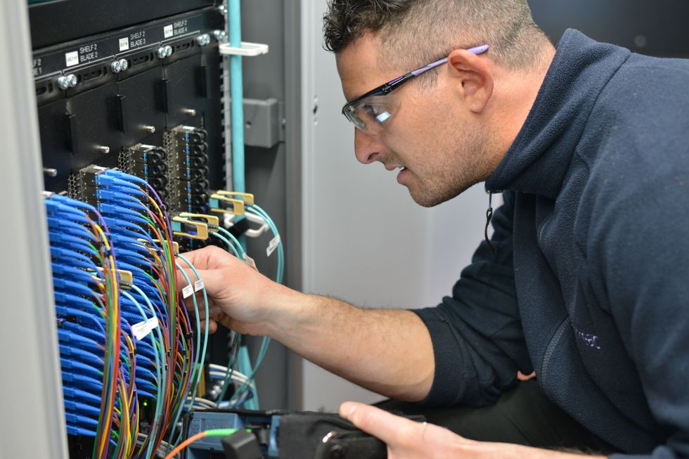 engineer fits cables into a cabinet to connect broadband