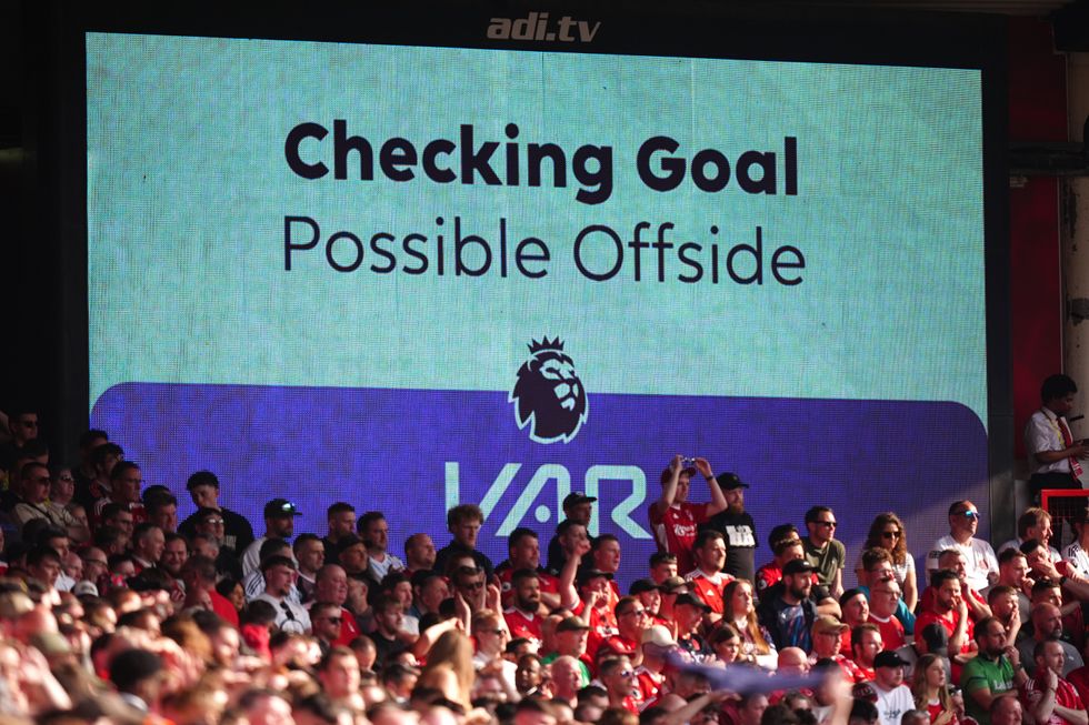 fans stand in the crowd watching the pitch while a screen confirms that a VAR check is taking place